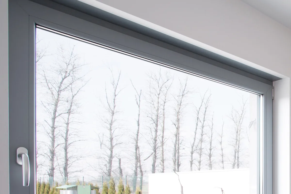 Large grey aluminium tilt and turn window over a kitchen sink, looking out to a garden