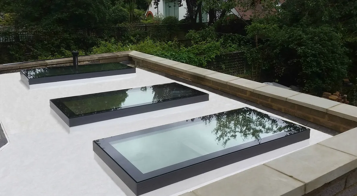 Three fixed flat rooflights with black borders on a flat roof